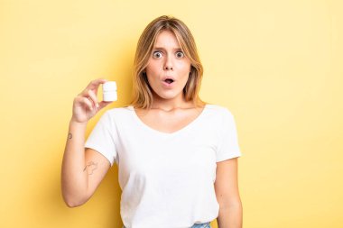 Güzel sarışın kız çok şaşırmış ya da şaşkın görünüyor. hap şişesi konsepti