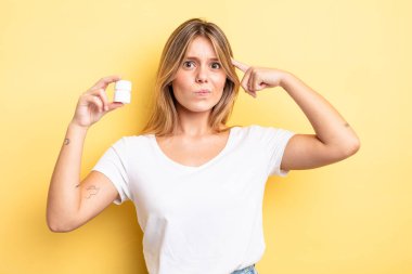 Güzel sarışın kız şaşkın ve şaşkın hissediyor, senin deli olduğunu gösteriyor. hap şişesi konsepti