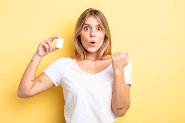 Güzel sarışın kız inançsızlıktan şaşkın şaşkın bakıyor. hap şişesi konsepti