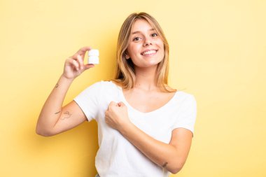 Güzel sarışın kız kendini mutlu hissediyor ve bir meydan okumayla yüzleşiyor ya da kutluyor. hap şişesi konsepti