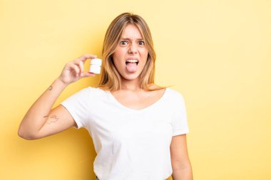 Güzel sarışın kız iğreniyor, sinirleniyor ve dilini çıkarıyor. hap şişesi konsepti