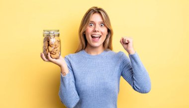 Güzel sarışın kız şokta, gülüyor ve başarıyı kutluyor. Ev yapımı kurabiye konsepti