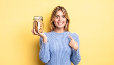 Güzel sarışın kız mutlu hissediyor ve heyecanla kendini işaret ediyor. Ev yapımı kurabiye konsepti