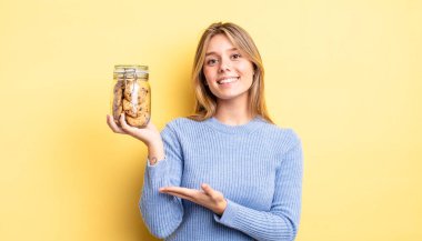 Güzel sarışın kız neşeyle gülümsüyor, mutlu hissediyor ve bir konsept gösteriyor. Ev yapımı kurabiye konsepti