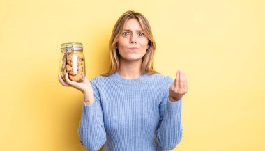 Güzel sarışın kız kapiş ya da para hareketi yapıyor, sana ödemeni söylüyor. Ev yapımı kurabiye konsepti