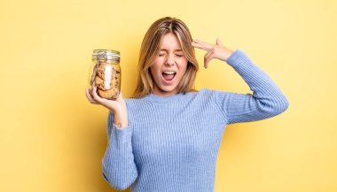 Güzel sarışın kız mutsuz ve stresli görünüyor, intihar jesti silah işareti yapıyor. Ev yapımı kurabiye konsepti