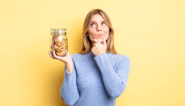 Güzel sarışın kız düşünüyor, kuşkulu ve şaşkın hissediyor. Ev yapımı kurabiye konsepti