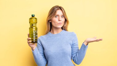 Güzel sarışın kız şaşkın, şaşkın ve şüpheci hissediyor. Zeytin yağı kavramı