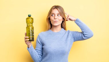 Güzel sarışın kız şaşkın ve kafası karışık, kaşınan bir kafa hissediyor. Zeytin yağı kavramı