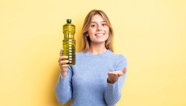 Güzel sarışın kız mutlu bir şekilde gülümsüyor ve bir konsept sunuyor. Zeytin yağı kavramı