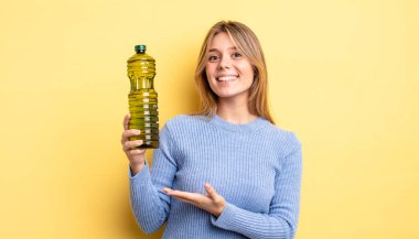 Güzel sarışın kız neşeyle gülümsüyor, mutlu hissediyor ve bir konsept gösteriyor. Zeytin yağı kavramı