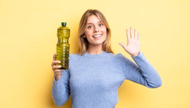 Güzel sarışın kız gülümsüyor ve arkadaş canlısı görünüyor, beş numarayı gösteriyor. Zeytin yağı kavramı