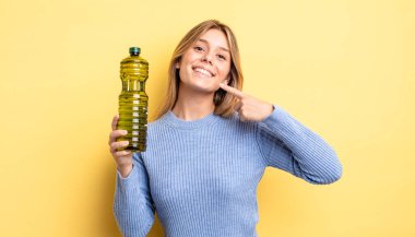 Güzel sarışın kız kendi gülüşünü göstererek kendine güvenerek gülümsüyor. Zeytin yağı kavramı