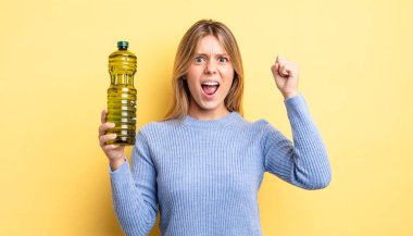 Güzel sarışın kız sinirli bir ifadeyle agresif bir şekilde bağırıyor. Zeytin yağı kavramı