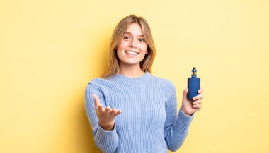 Güzel sarışın kız mutlu bir şekilde gülümsüyor ve bir konsept sunuyor. duman buharlaştırıcı kavramı