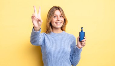 Güzel sarışın kız gülümsüyor ve mutlu görünüyor, zafer ya da barış işareti yapıyor. duman buharlaştırıcı kavramı