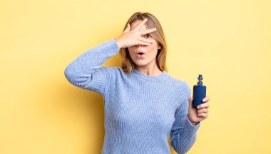 Güzel sarışın kız şok olmuş, korkmuş ya da korkmuş görünüyor. Yüzü elle kapatılmış. duman buharlaştırıcı kavramı