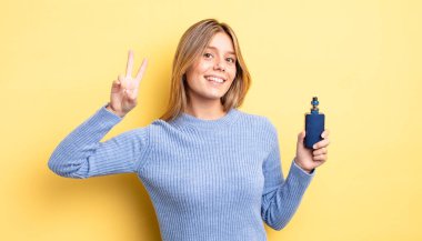 Güzel sarışın kız gülümsüyor ve arkadaş canlısı görünüyor. İki numarayı gösteriyor. duman buharlaştırıcı kavramı