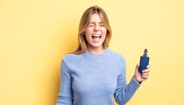 Güzel sarışın kız agresif bir şekilde bağırıyor, çok kızgın görünüyor. duman buharlaştırıcı kavramı