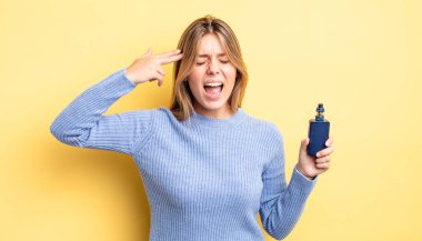 Güzel sarışın kız mutsuz ve stresli görünüyor, intihar jesti silah işareti yapıyor. duman buharlaştırıcı kavramı