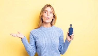 Güzel sarışın kız şaşırmış ve şok olmuş görünüyor. Çenesi düşmüş ve elinde bir nesne var. duman buharlaştırıcı kavramı