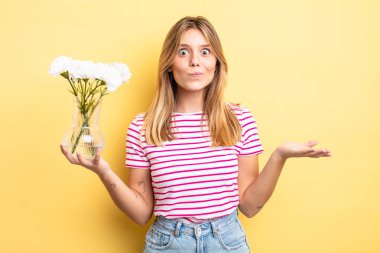 Güzel sarışın kız şaşkın, şaşkın ve şüpheci hissediyor. Dekoratif çiçek konsepti