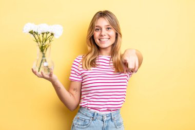 Güzel sarışın kız seni seçen kamerayı işaret ediyor. Dekoratif çiçek konsepti