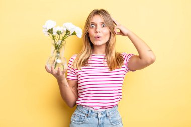Güzel sarışın kız mutlu, şaşkın ve şaşırmış görünüyor. Dekoratif çiçek konsepti