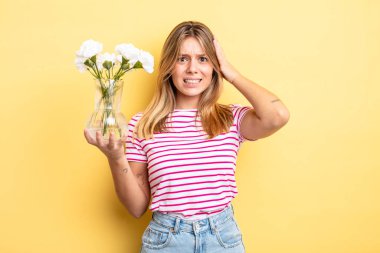 Güzel sarışın kız stresli, endişeli ya da korkmuş, elleri başının üstünde. Dekoratif çiçek konsepti