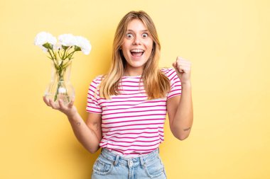 Güzel sarışın kız şokta, gülüyor ve başarıyı kutluyor. Dekoratif çiçek konsepti