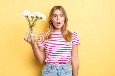 Güzel sarışın kız çok şaşırmış ya da şaşkın görünüyor. Dekoratif çiçek konsepti