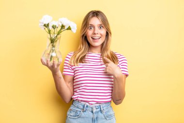 Güzel sarışın kız mutlu hissediyor ve heyecanla kendini işaret ediyor. Dekoratif çiçek konsepti