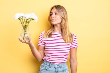 Profil görünümündeki güzel sarışın kız hayal mi kuruyor, hayal mi kuruyor yoksa hayal mi kuruyor? Dekoratif çiçek konsepti