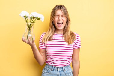 Güzel sarışın kız agresif bir şekilde bağırıyor, çok kızgın görünüyor. Dekoratif çiçek konsepti