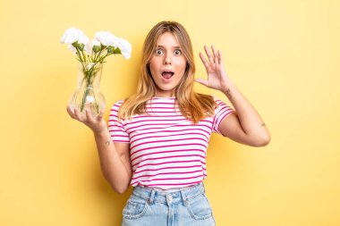 Güzel sarışın kız ellerini havaya kaldırarak çığlık atıyor. Dekoratif çiçek konsepti