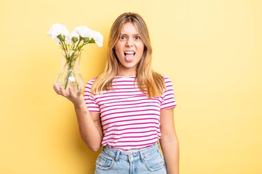 Güzel sarışın kız iğreniyor, sinirleniyor ve dilini çıkarıyor. Dekoratif çiçek konsepti