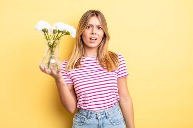Güzel sarışın kız şaşkın ve şaşkın hissediyor. Dekoratif çiçek konsepti