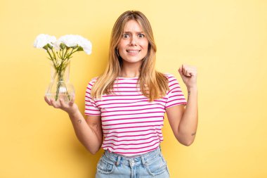 Güzel sarışın kız sinirli bir ifadeyle agresif bir şekilde bağırıyor. Dekoratif çiçek konsepti