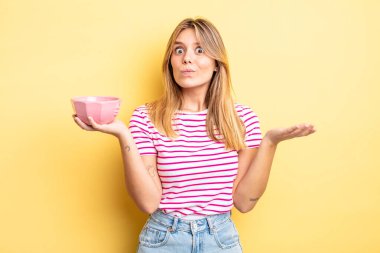 Güzel sarışın kız şaşkın, şaşkın ve şüpheci hissediyor. boş kase kavramı