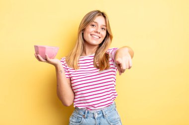 Güzel sarışın kız seni seçen kamerayı işaret ediyor. boş kase kavramı