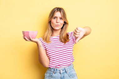 Güzel sarışın kız kendini kötü hissediyor, baş parmağını kaldırıyor. boş kase kavramı