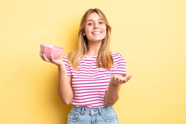 Güzel sarışın kız mutlu bir şekilde gülümsüyor ve bir konsept sunuyor. boş kase kavramı