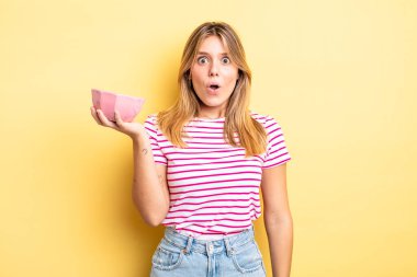 Güzel sarışın kız çok şaşırmış ya da şaşkın görünüyor. boş kase kavramı