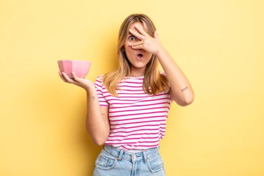 Güzel sarışın kız şok olmuş, korkmuş ya da korkmuş görünüyor. Yüzü elle kapatılmış. boş kase kavramı