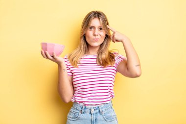 Güzel sarışın kız şaşkın ve şaşkın hissediyor, senin deli olduğunu gösteriyor. boş kase kavramı