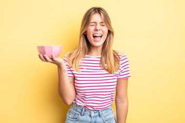 Güzel sarışın kız agresif bir şekilde bağırıyor, çok kızgın görünüyor. boş kase kavramı