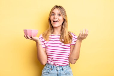 Güzel sarışın kız kendini mutlu hissediyor, bir çözüm ya da fikir bulduğuna şaşırıyor. boş kase kavramı