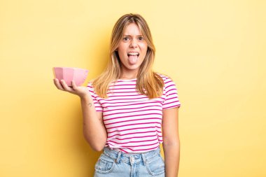 Güzel sarışın kız iğreniyor, sinirleniyor ve dilini çıkarıyor. boş kase kavramı