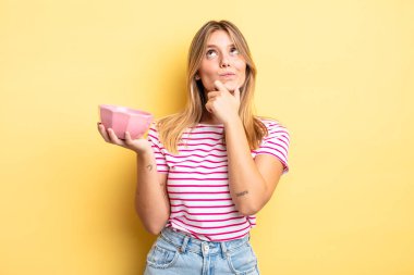 Güzel sarışın kız düşünüyor, kuşkulu ve şaşkın hissediyor. boş kase kavramı