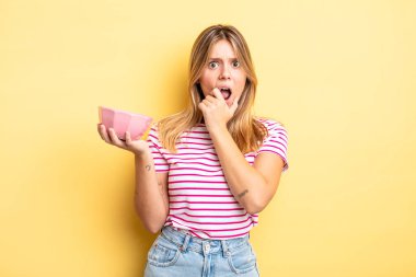 Güzel sarışın kız, ağzı ve gözleri sonuna kadar açık ve eli çenesinde. boş kase kavramı